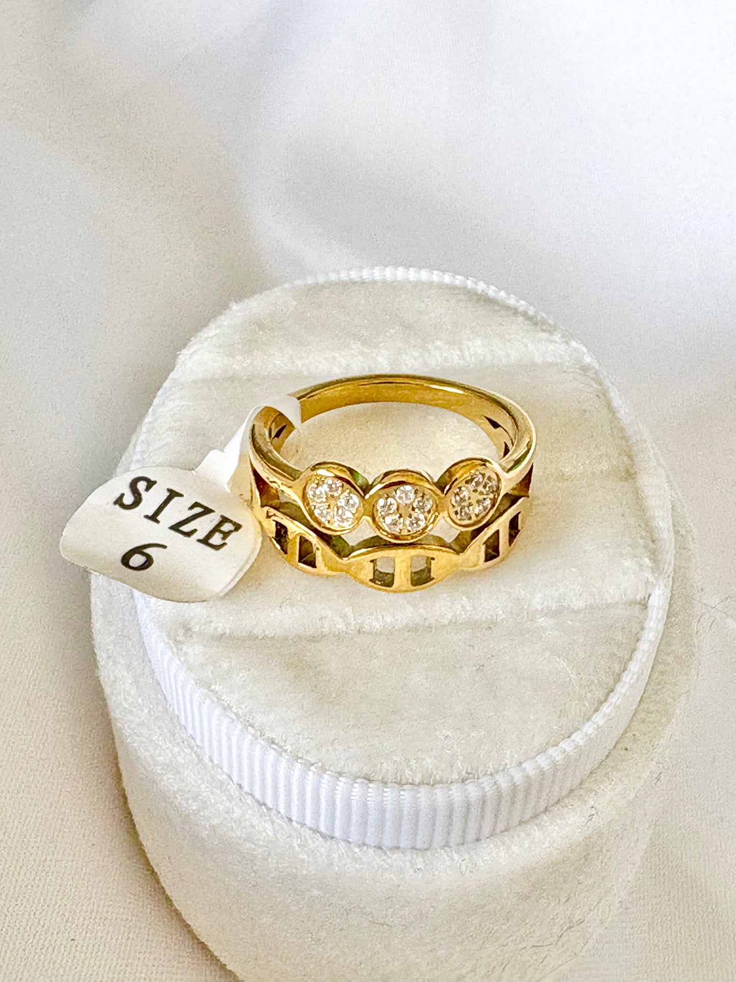A gold ring with three round clear gemstones SIZE 6.