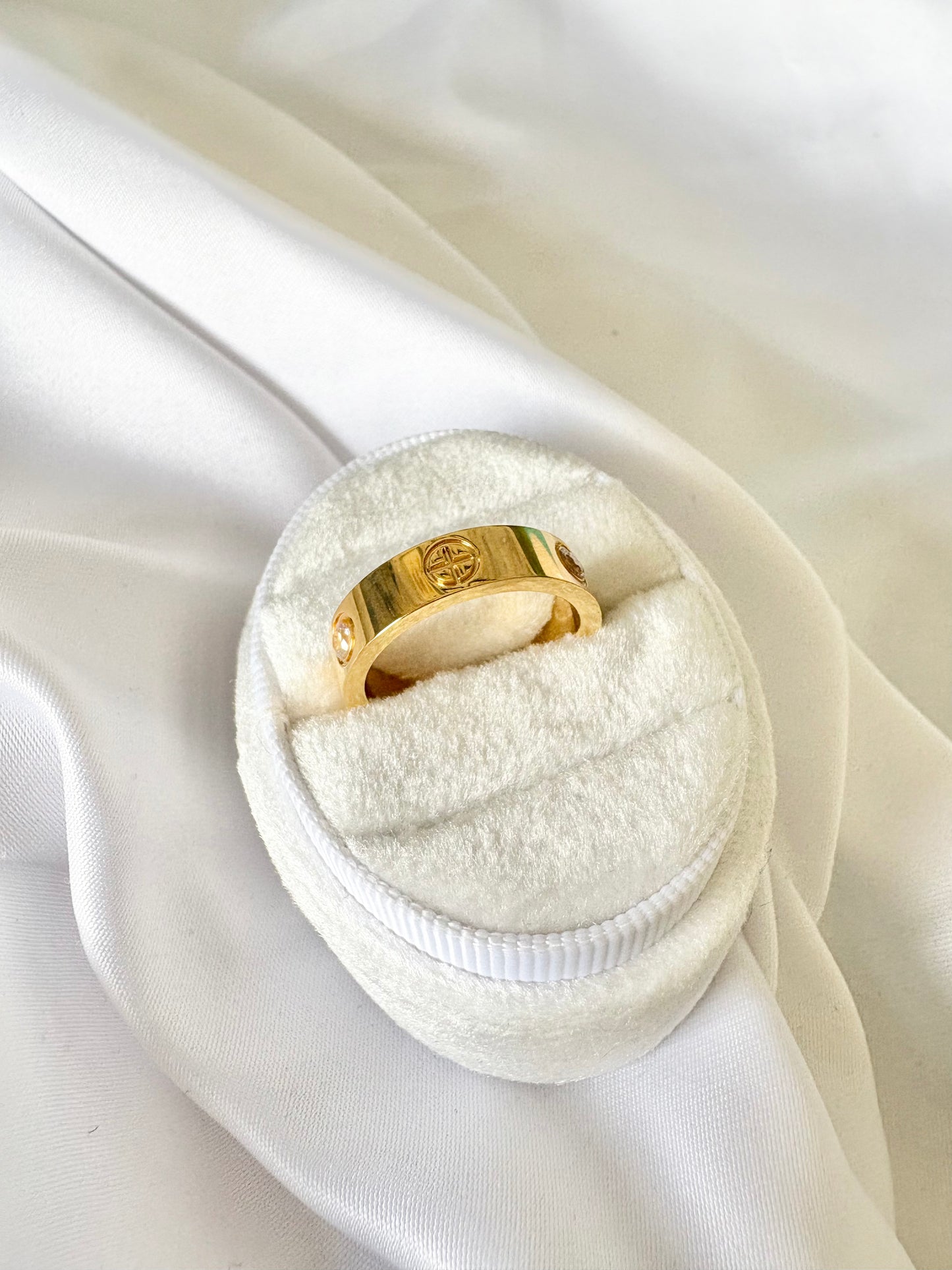A gold band ring with engraved screw.