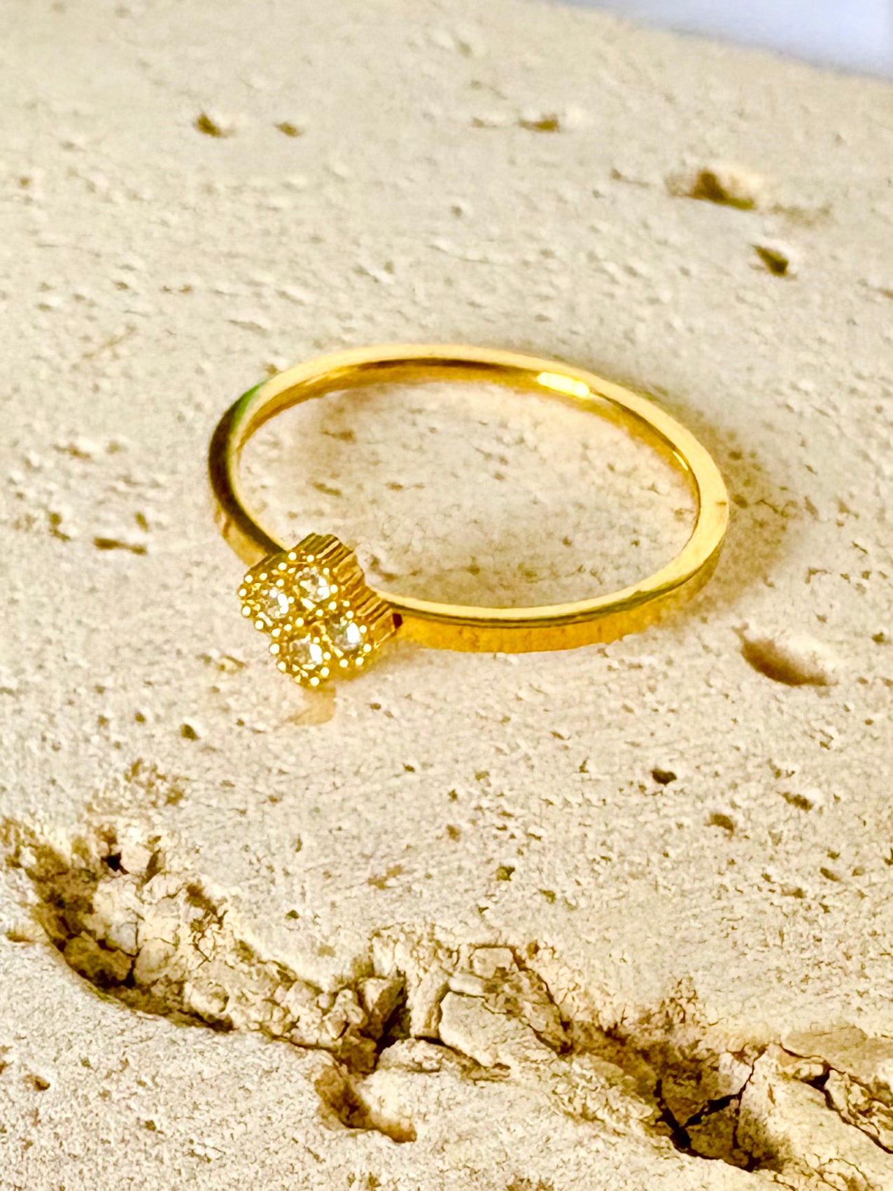 A gold ring with a textured, multi-stone square-shaped setting