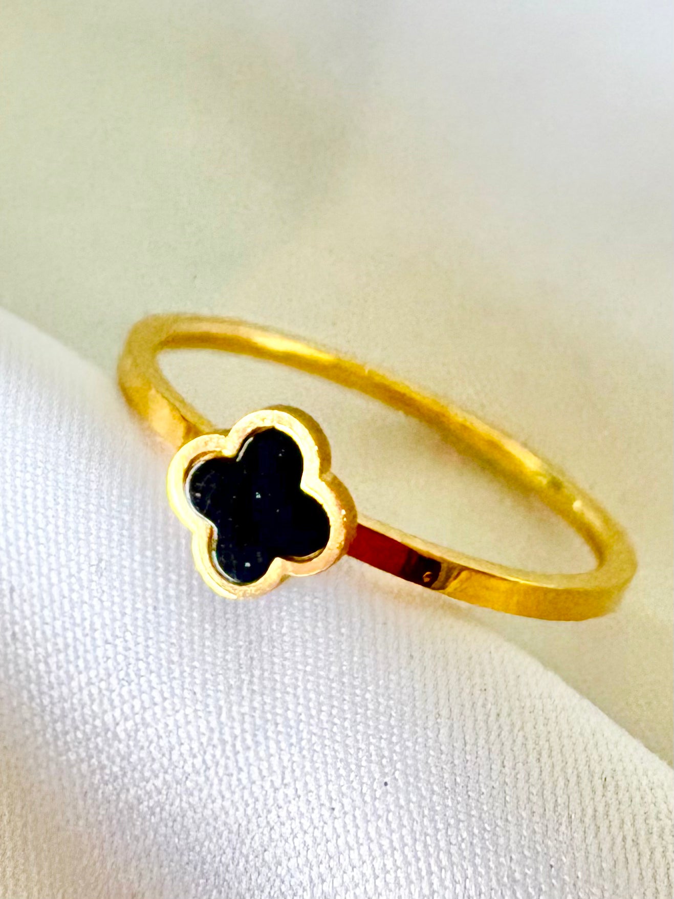 A gold ring featuring a clover-shaped face with a black inlay.