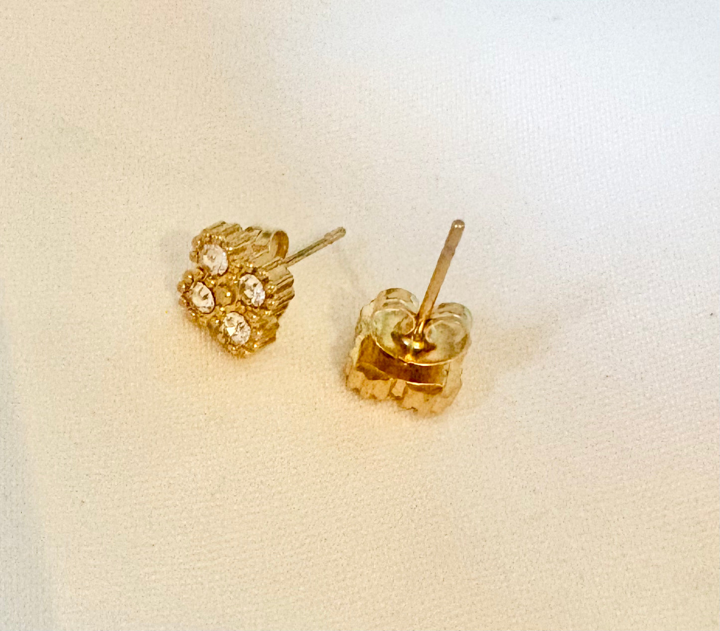 A pair of gold stud earrings with a textured floral cluster design and clear rhinestones