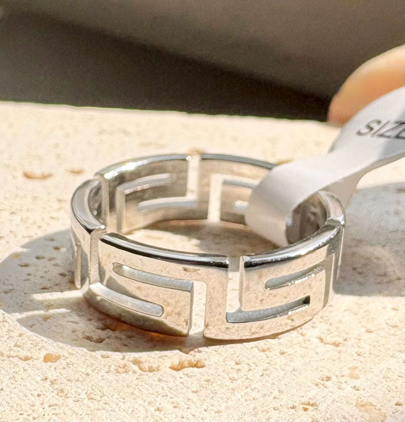 A stainless steel band ring with a Greek key pattern