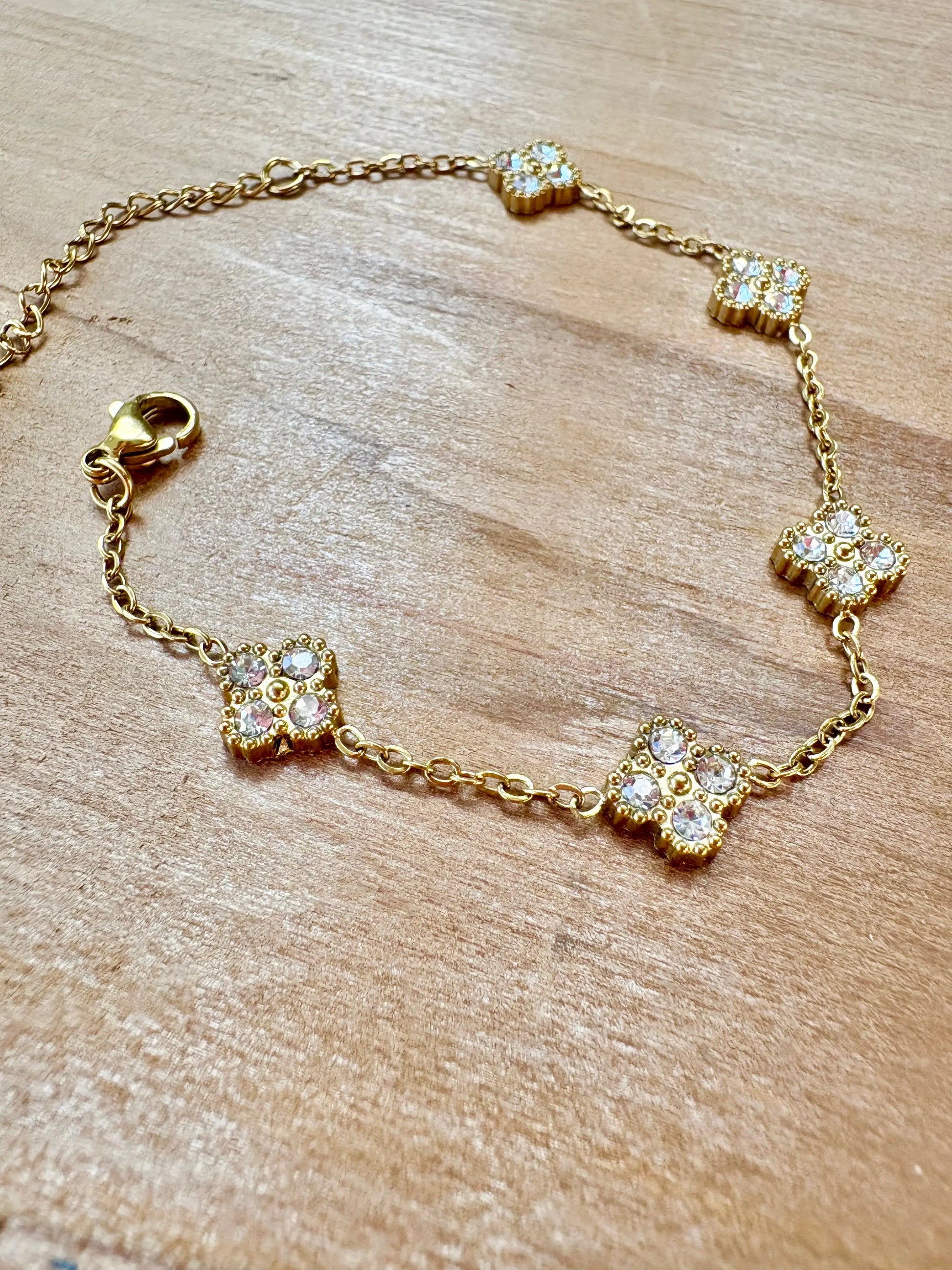 A gold chain bracelet with five small clover-shaped charms