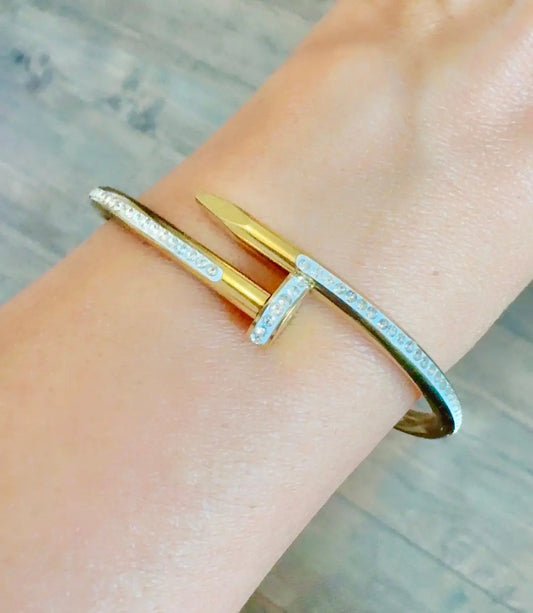 A close-up of a gold bangle bracelet with zircon clear stones