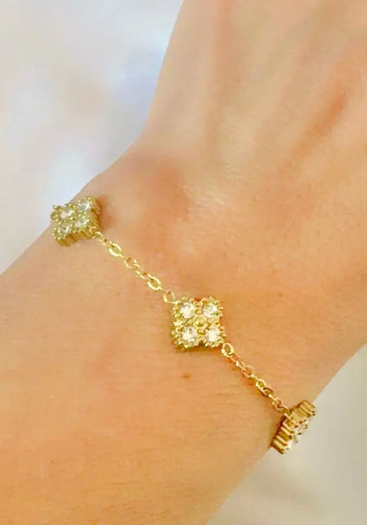 A delicate gold chain bracelet with five small clover clusters of zircon stones