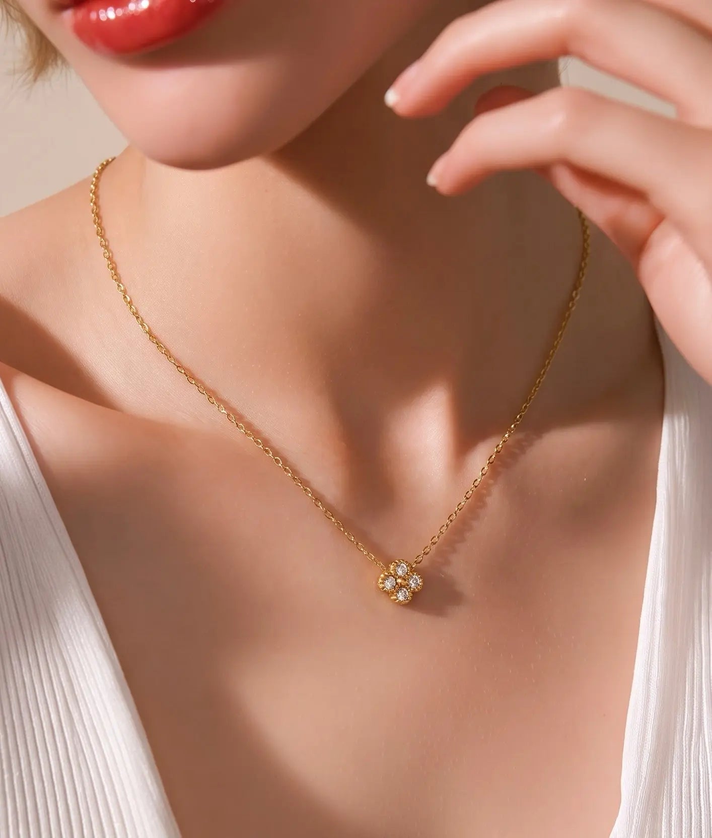 A close-up lifestyle shot of a model wearing a delicate gold chain necklace with a small clover pendant
