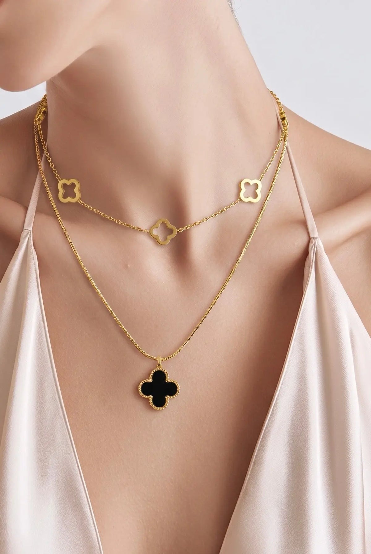 A close-up of a model wearing a layered gold necklace set. 