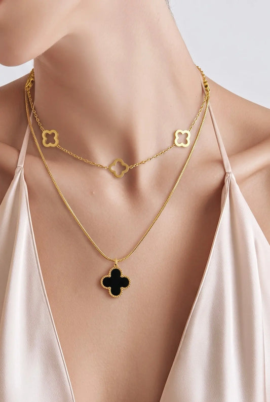 A close-up of a model wearing a layered gold necklace set. 