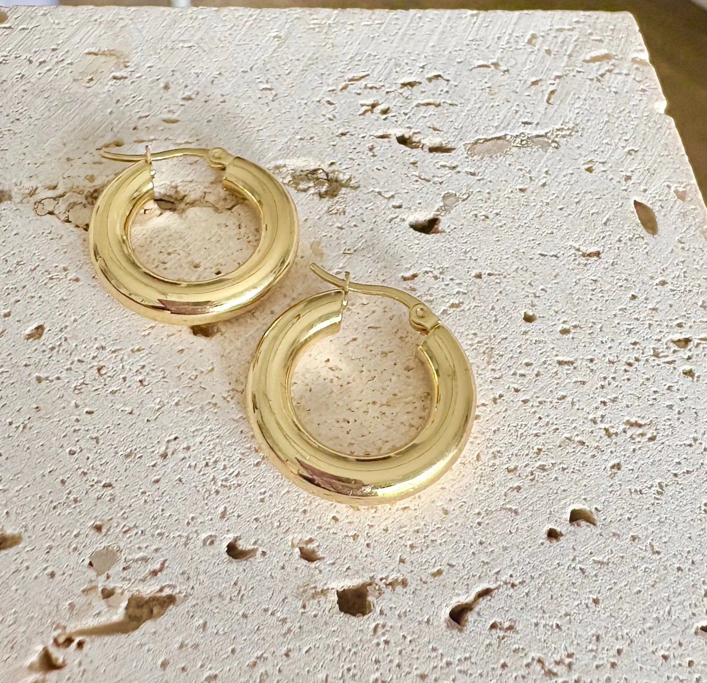 A pair of chunky, gold hoop earrings.