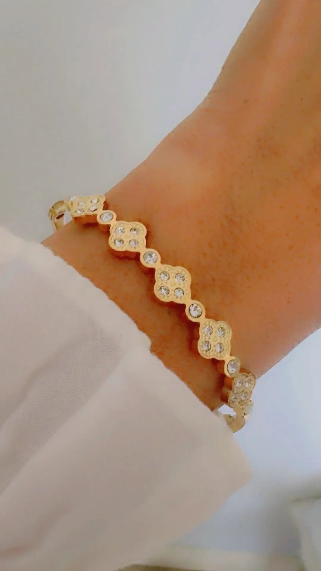 A gold-toned bracelet with repeating clover motifs .
