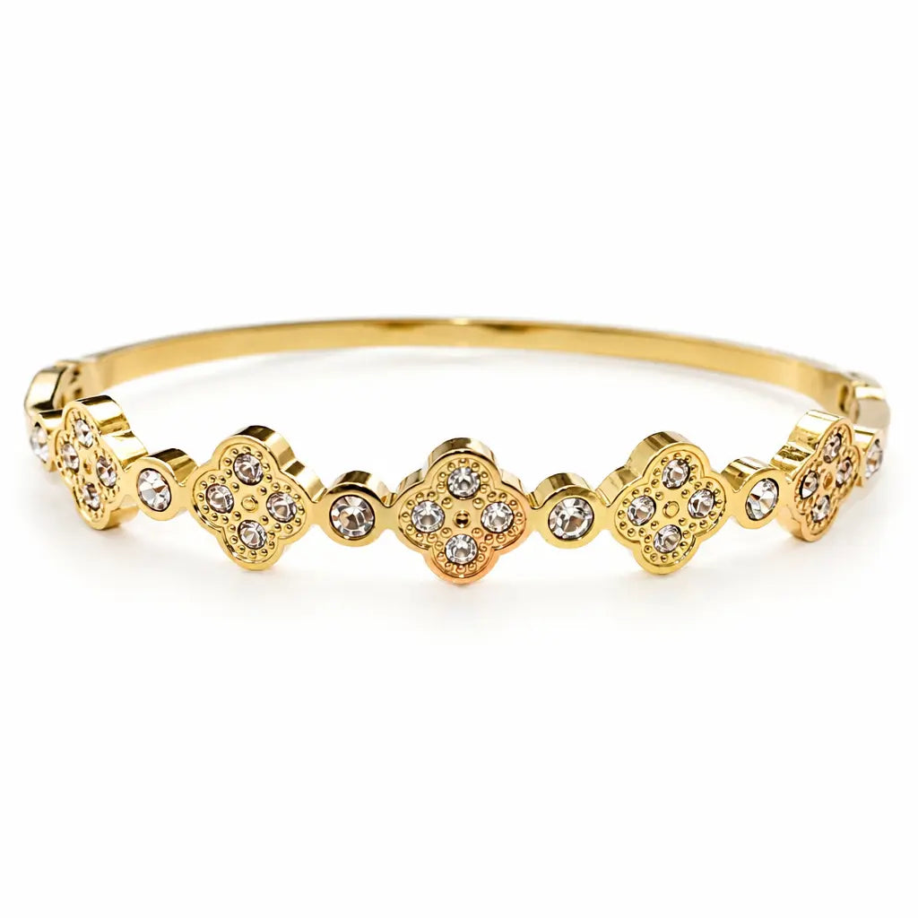 A gold bangle bracelet featuring a row of clovers motifs set with small zircon stones.