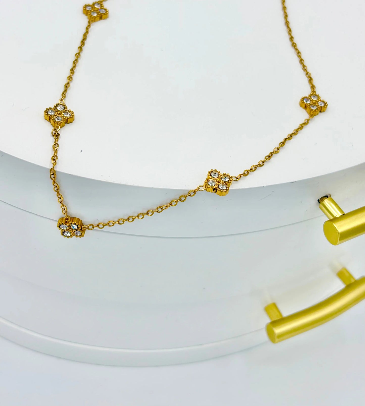 A gold chain necklace with five small floral clover motifs