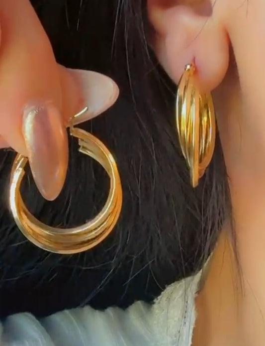 Layered gold hoop earrings with three interwoven hoops displayed on ear