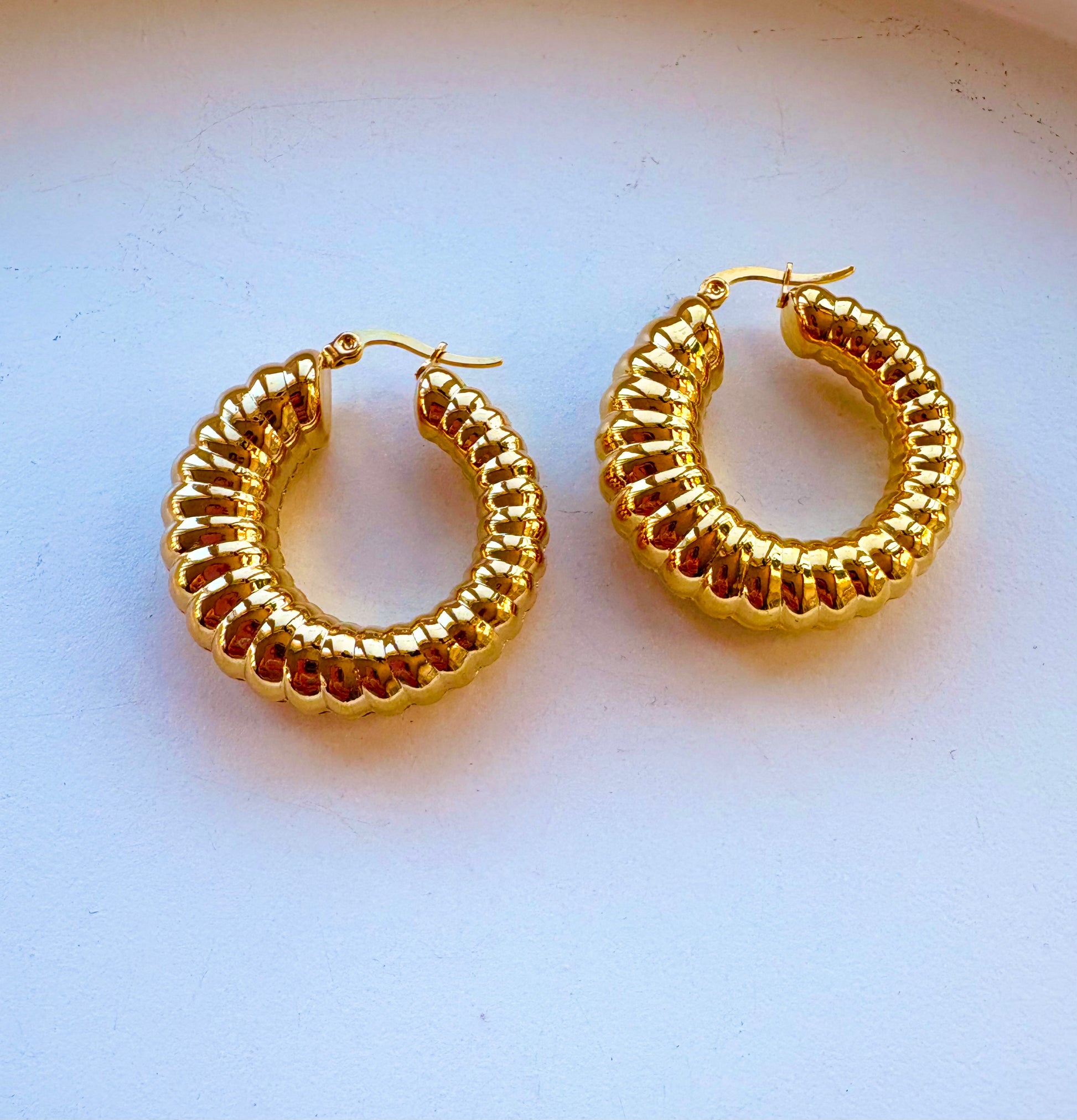Close-up of 18K gold plated chunky hoop earrings showing ribbed texture and shiny finish.