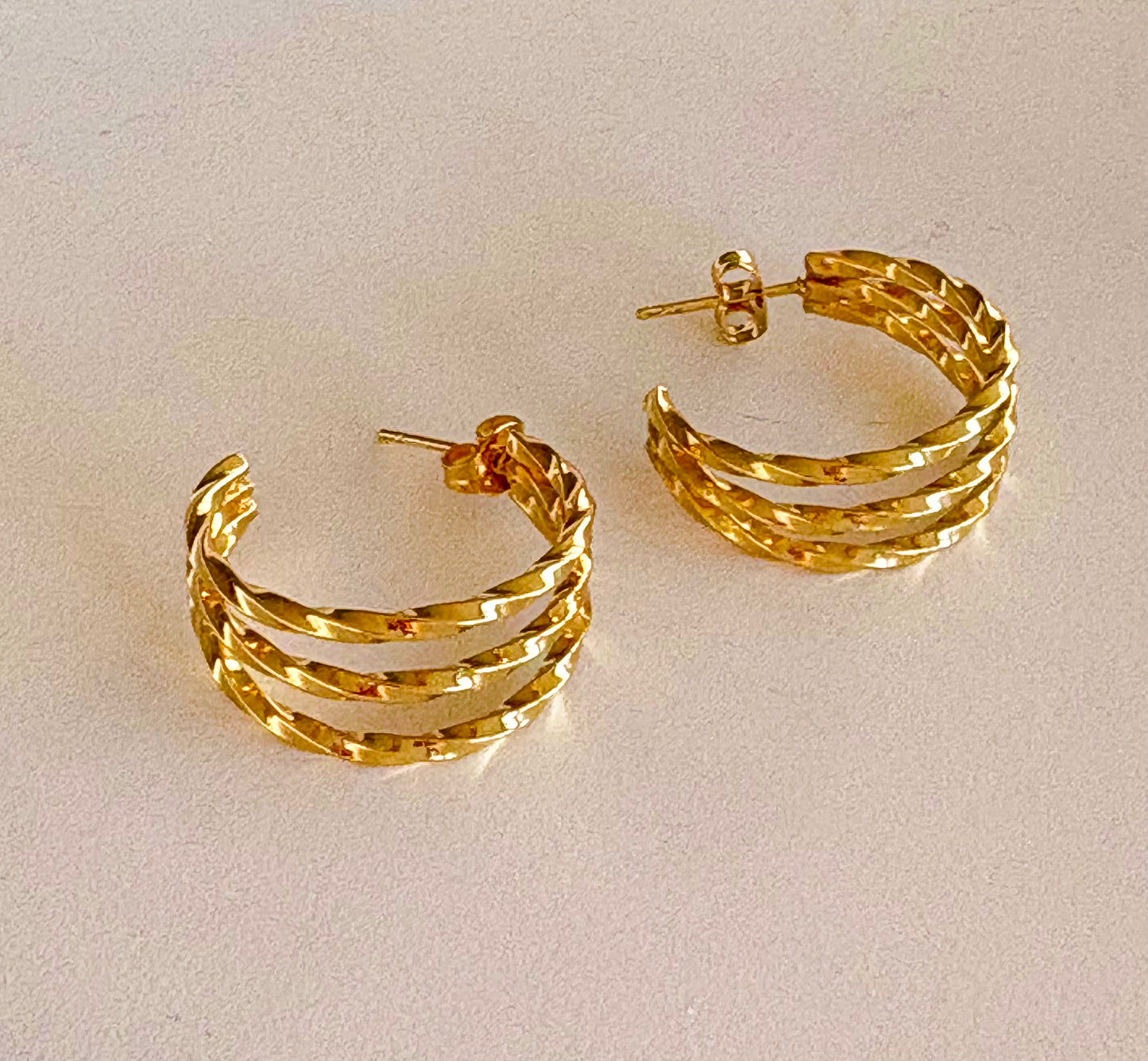 Close‑up of the hammered texture on a gold triple‑band hoop earring, highlighting its layered bands