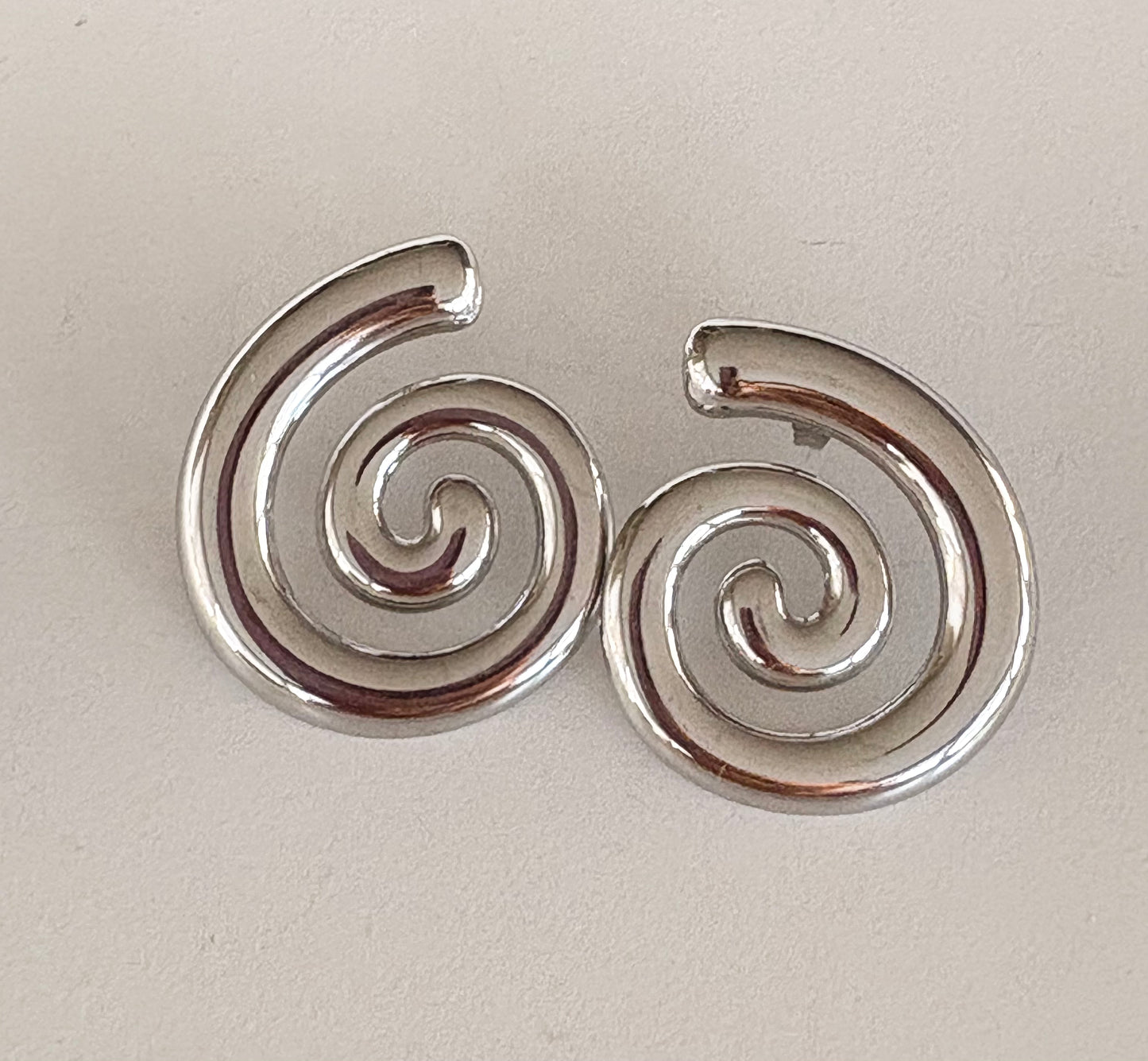 Pair of silver spiral earrings on a light beige background
