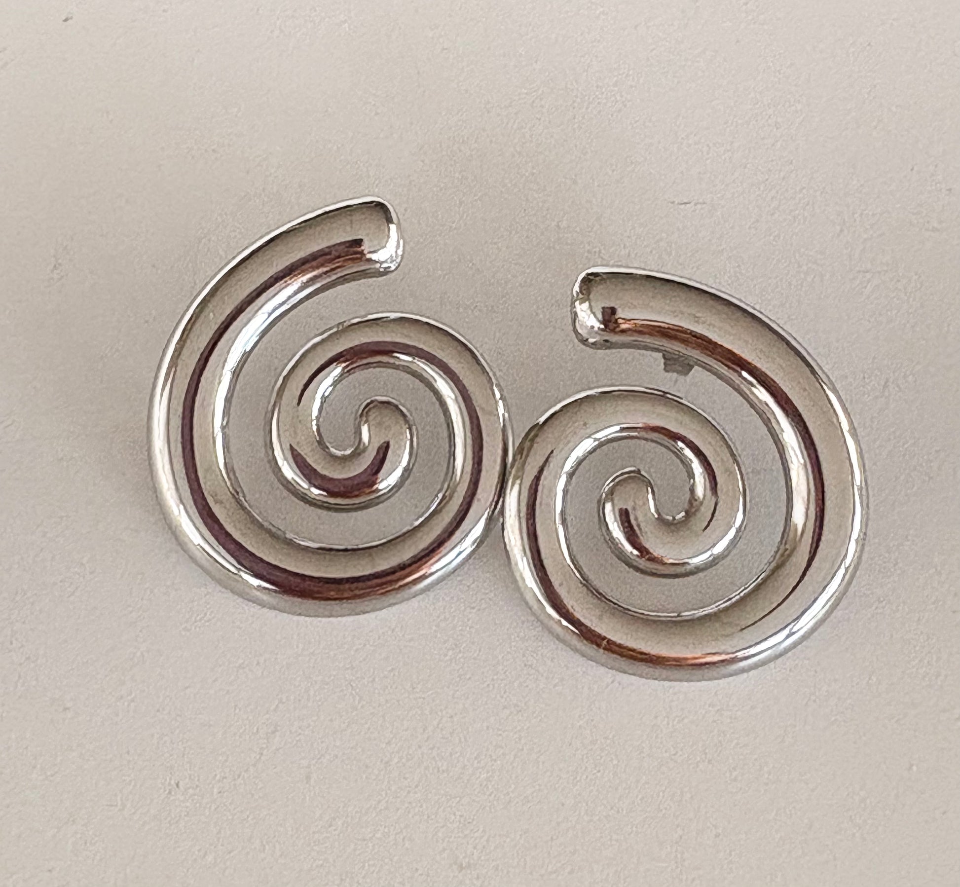 Pair of silver spiral earrings on a light beige background