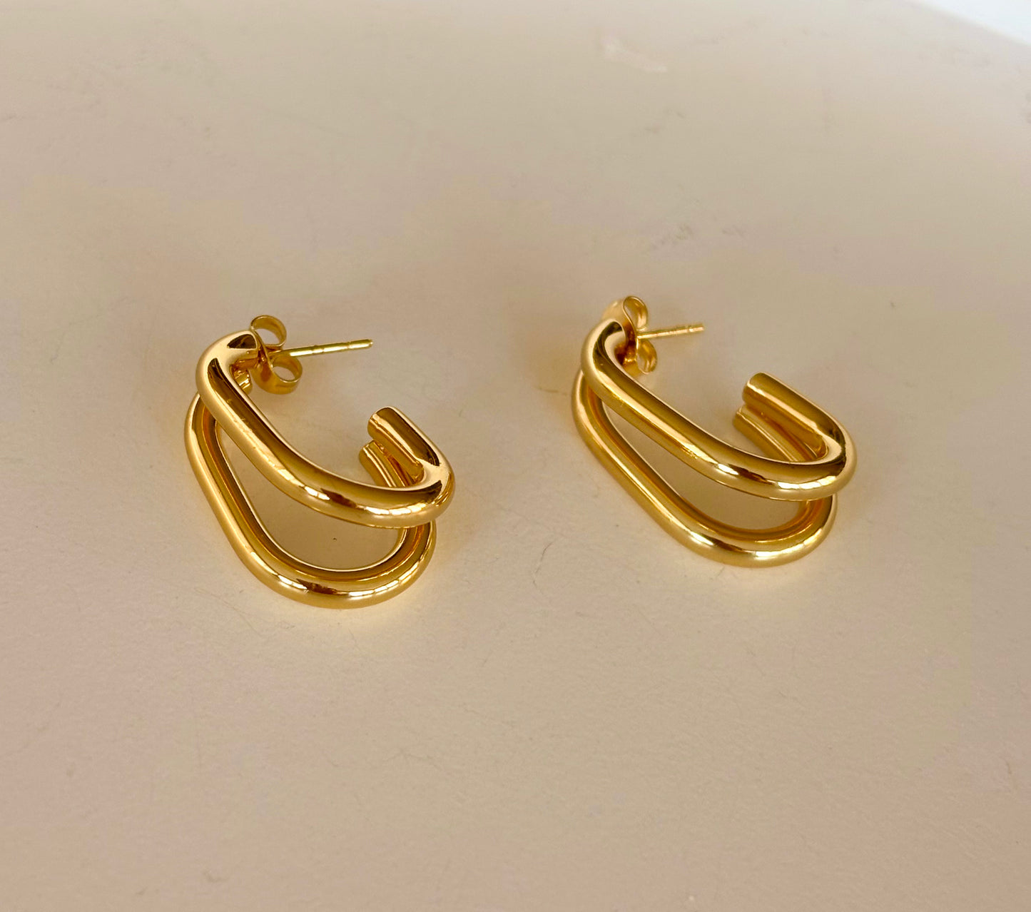 Close‑up of gold double‑layer rectangular hoop earrings highlighting their polished finish and parallel loops