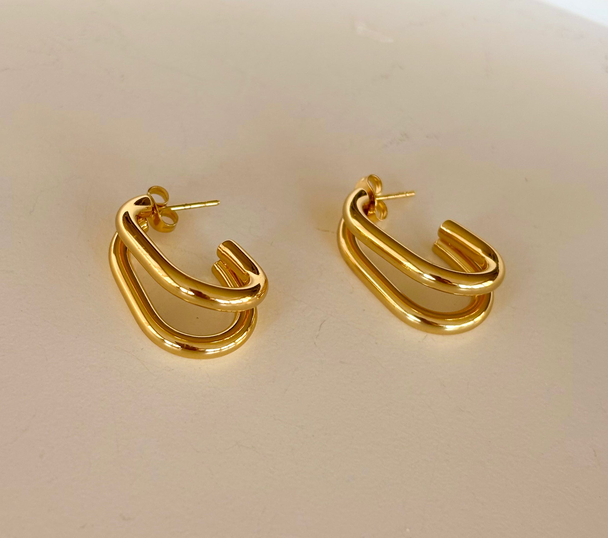 Close‑up of gold double‑layer rectangular hoop earrings highlighting their polished finish and parallel loops