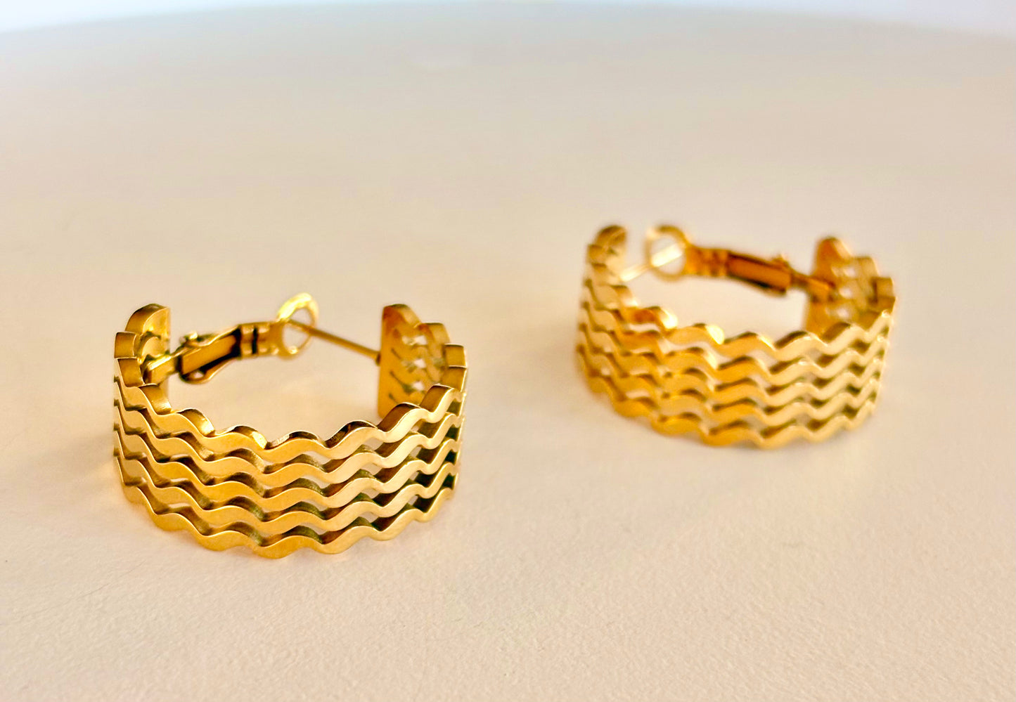 Side angle showing the chunky profile and secure latch closure of the 3 cm wavy gold hoop earrings.