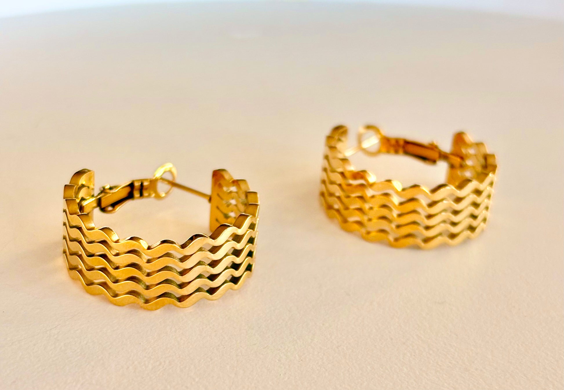 Side angle showing the chunky profile and secure latch closure of the 3 cm wavy gold hoop earrings.