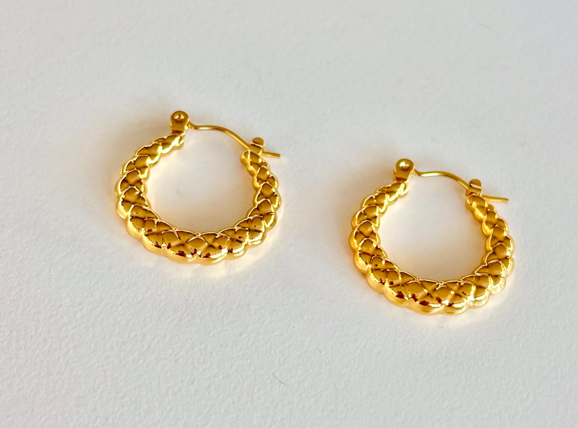 Pair of small woven gold hoop earrings showing the 2 cm size and braided texture