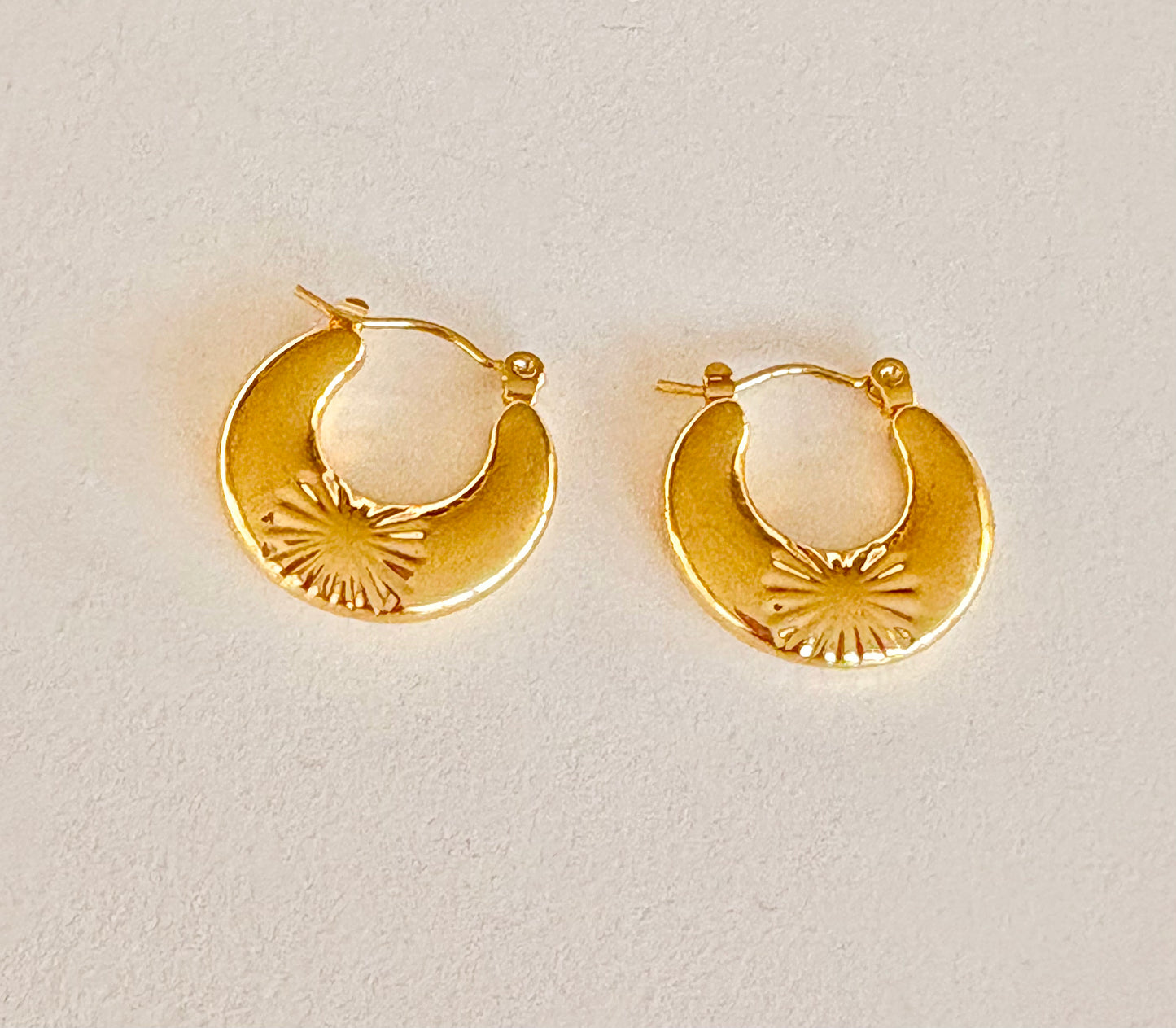 Pair of small starburst crescent hoop earrings showing their polished 18k gold‑plated finish