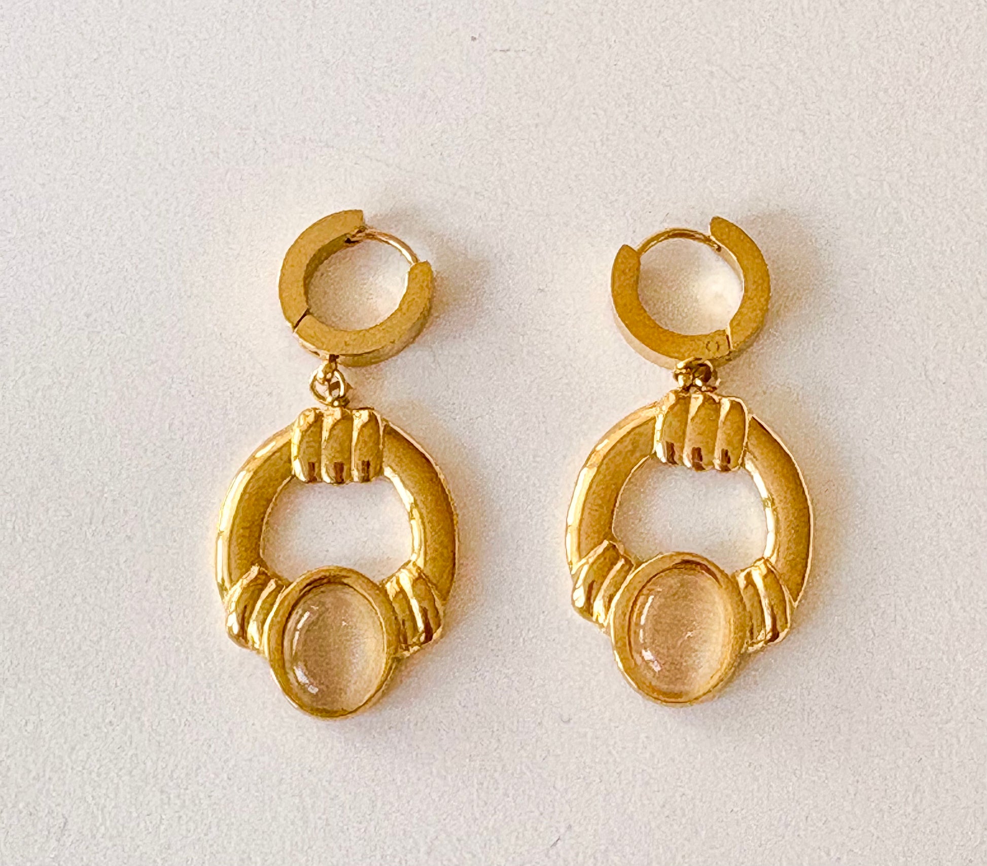 Front view of gold‑plated hoop dangle earrings featuring oval cabochon stones and ridged detailing