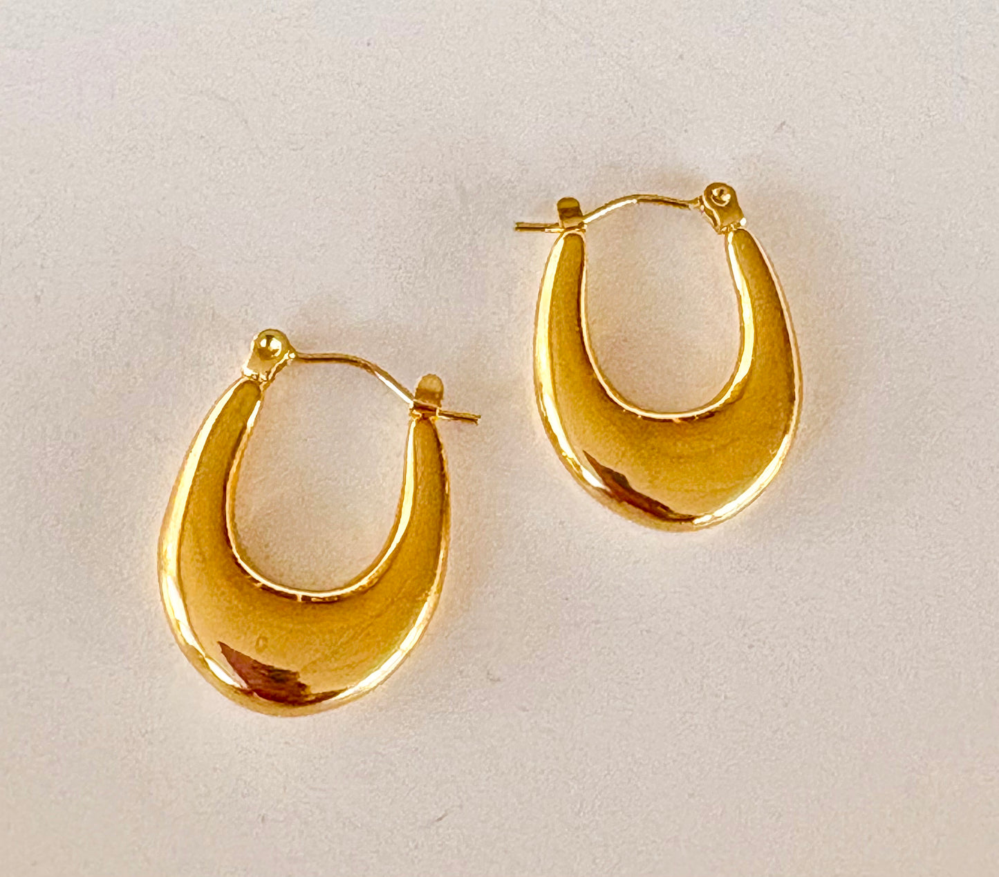 Pair of 18k gold‑plated crescent hoop earrings showing a smooth, curved design