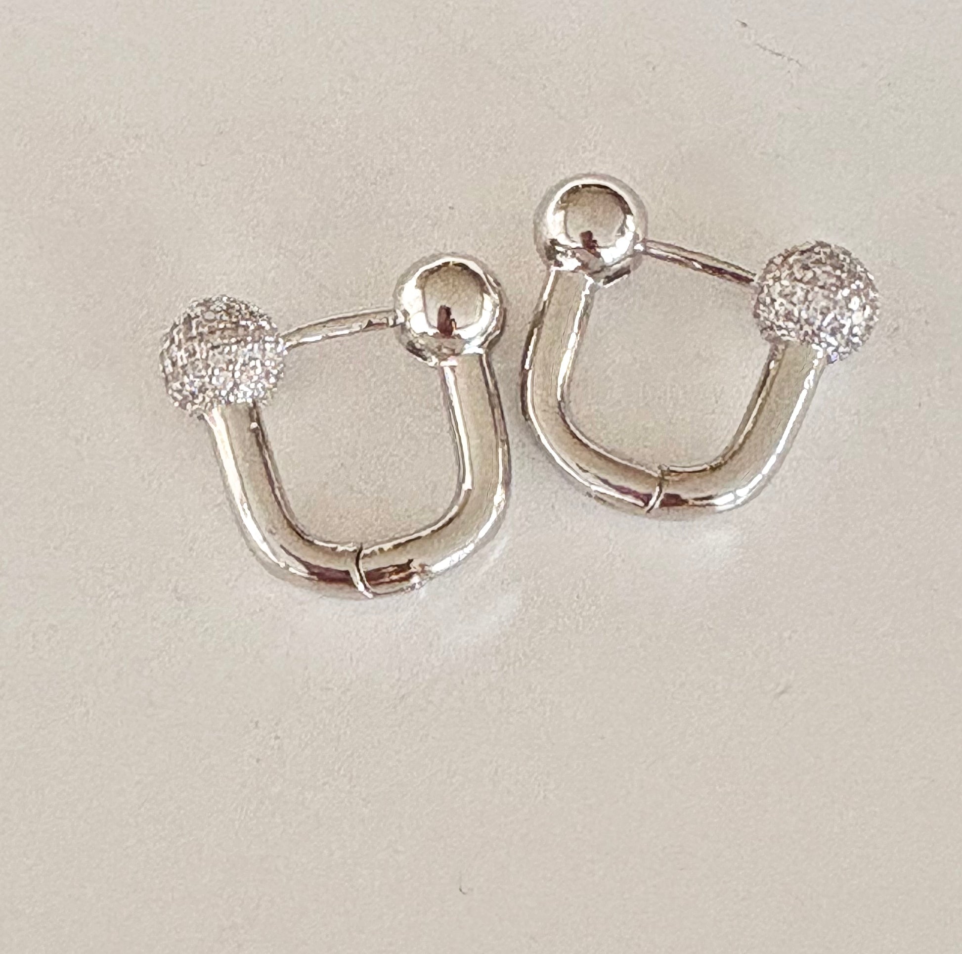 Pair of white‑gold–plated U‑shaped hoop earrings showing hypoallergenic stainless steel design.