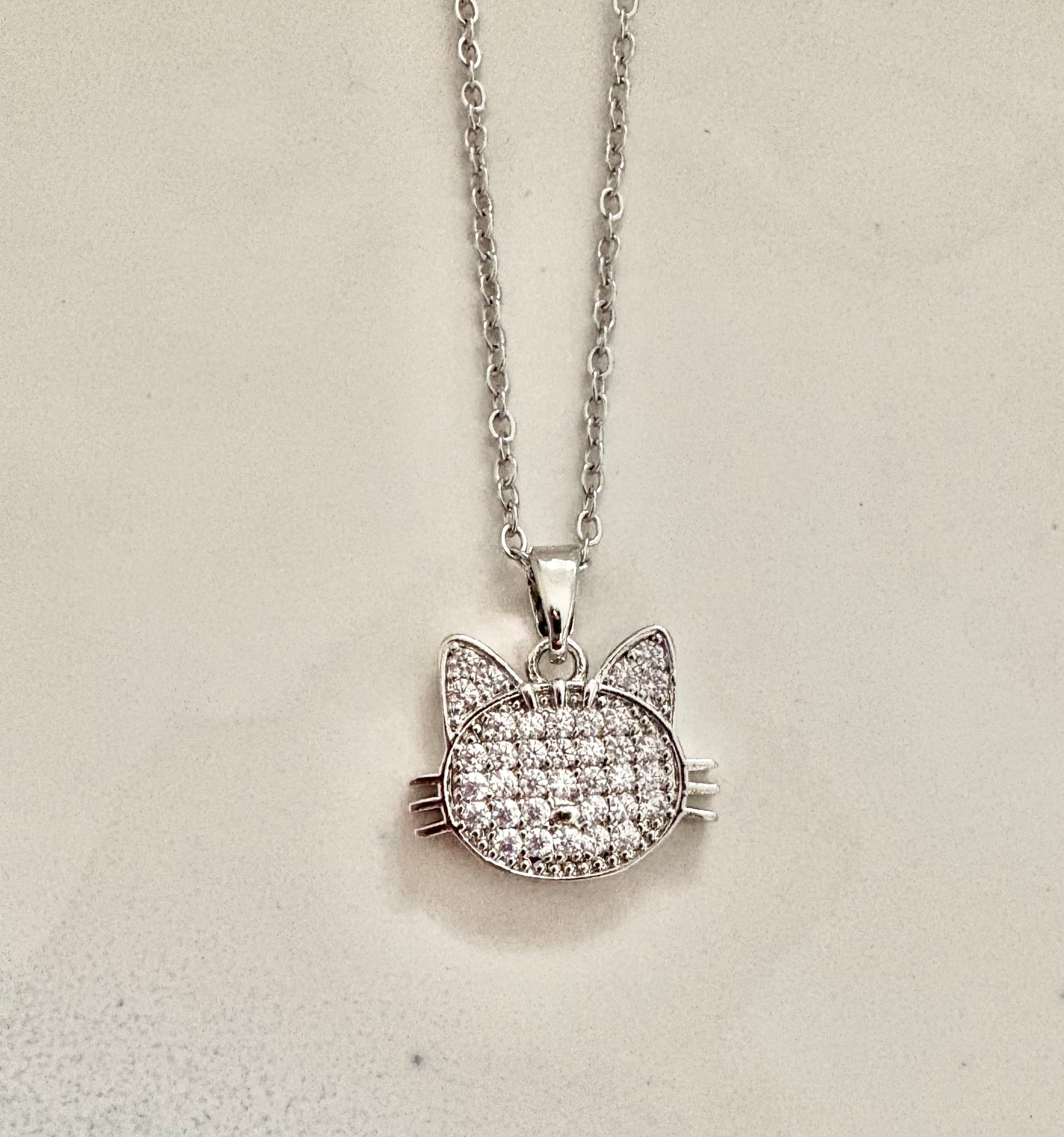 Cat-shaped pendant necklace on a light beige background