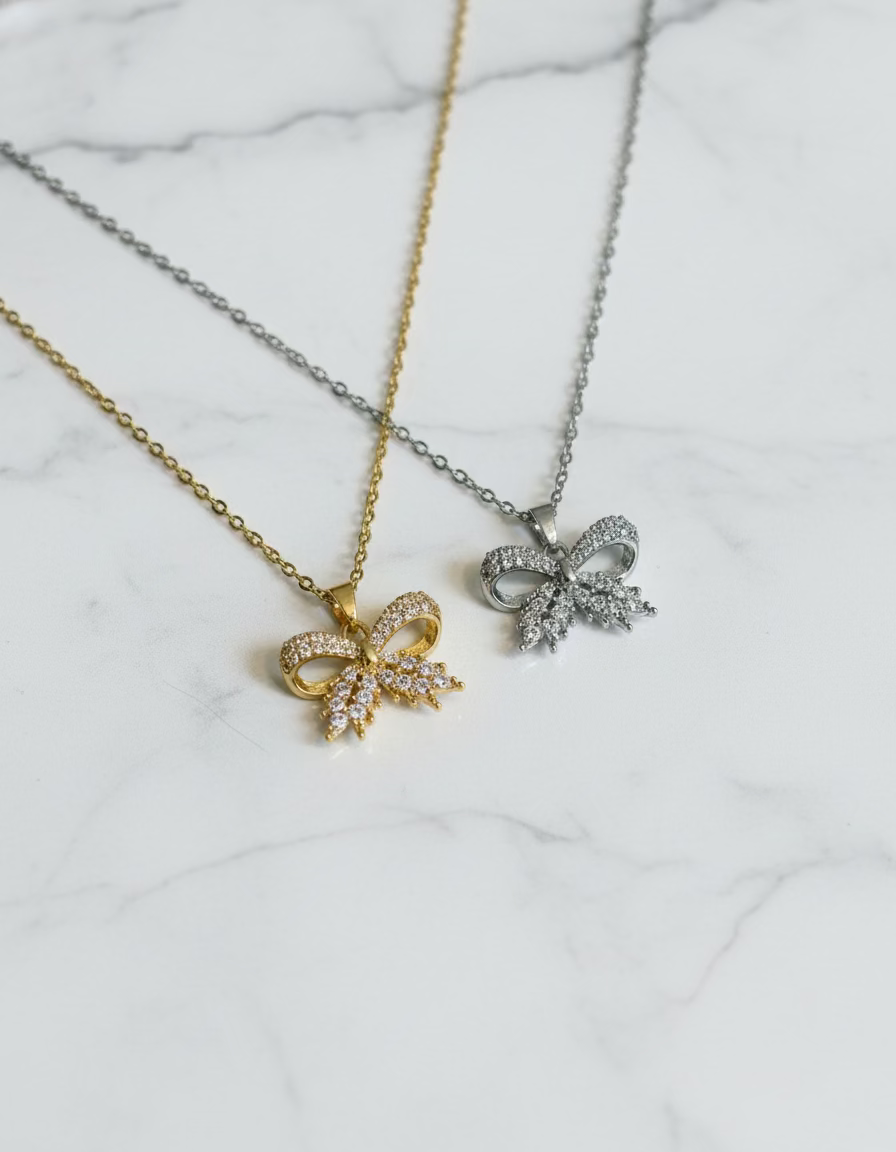 Elegant bow pendant necklace in gold & silver. 18K gold-plated, waterproof, non-tarnish design with sparkling crystals.