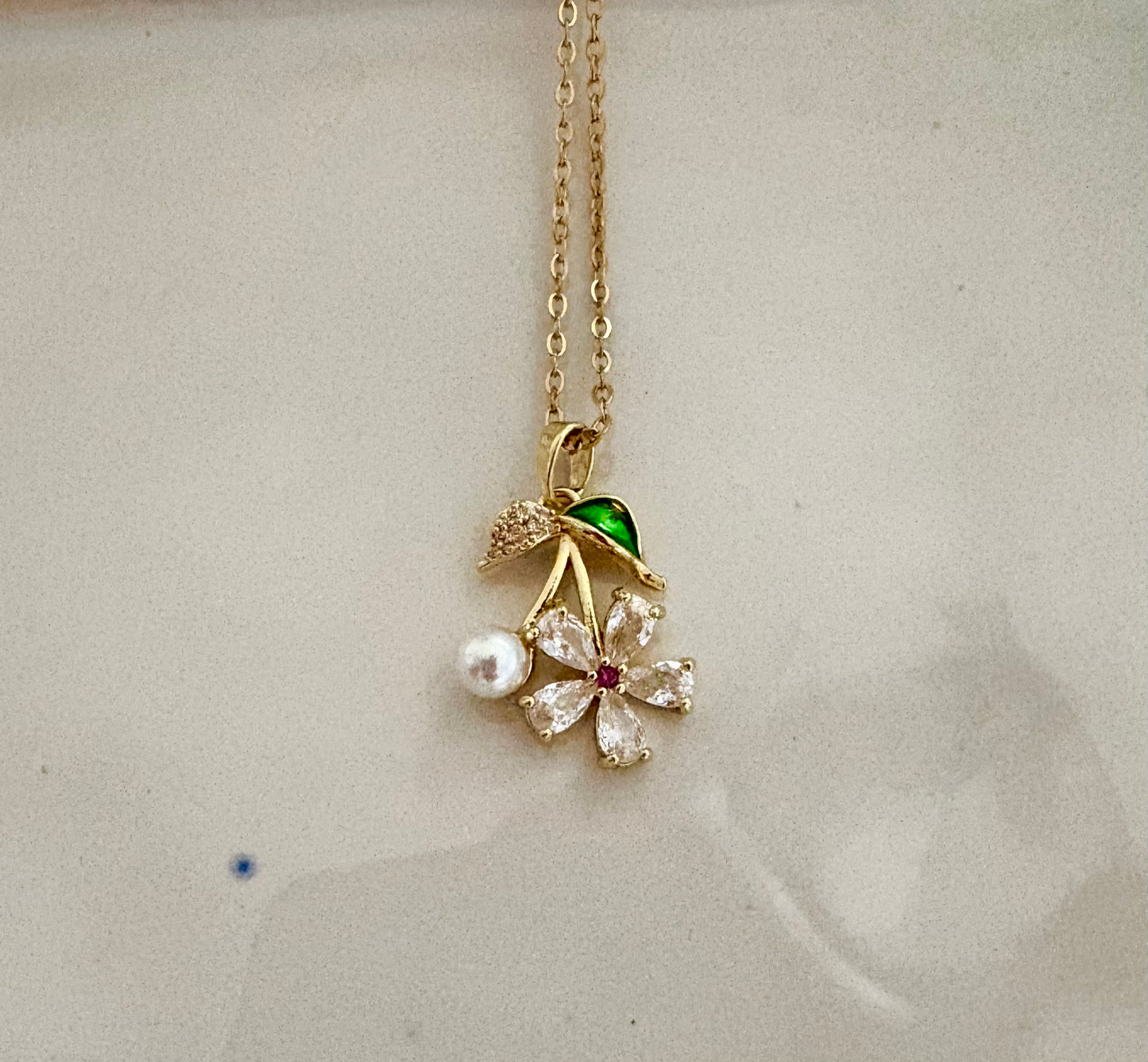 Elegant floral jewelry with pearl and green enamel leaf design.