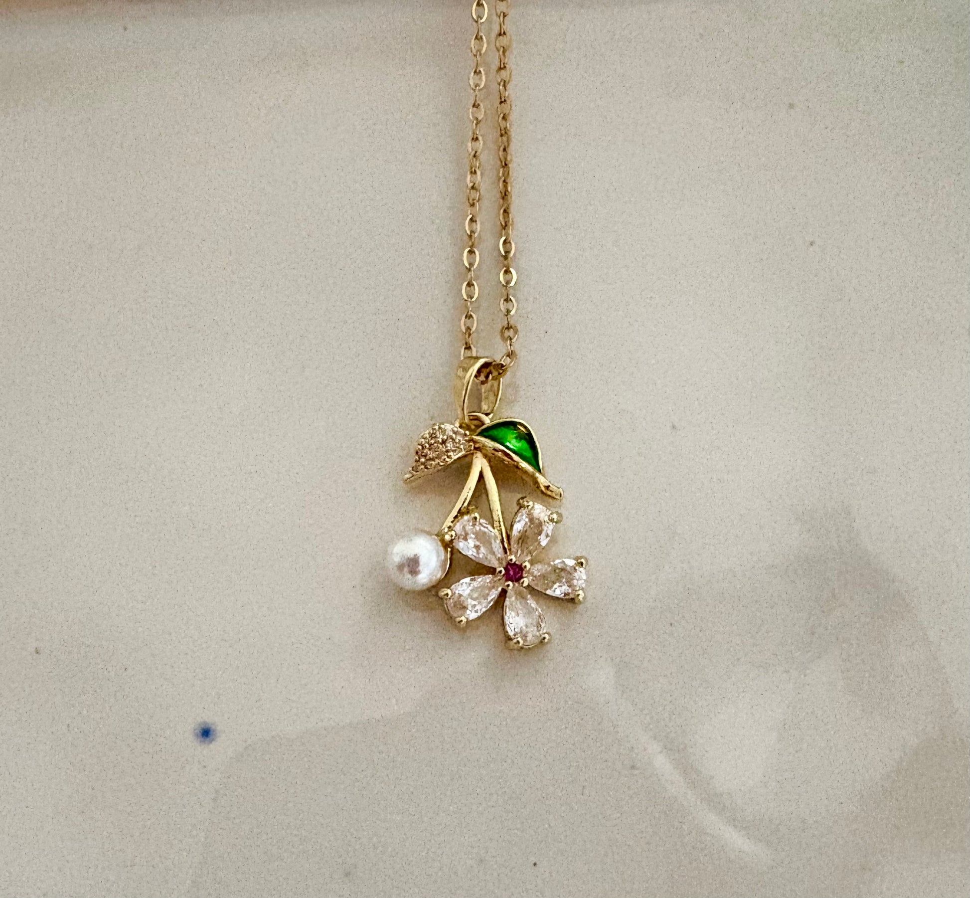 Elegant floral jewelry with pearl and green enamel leaf design.