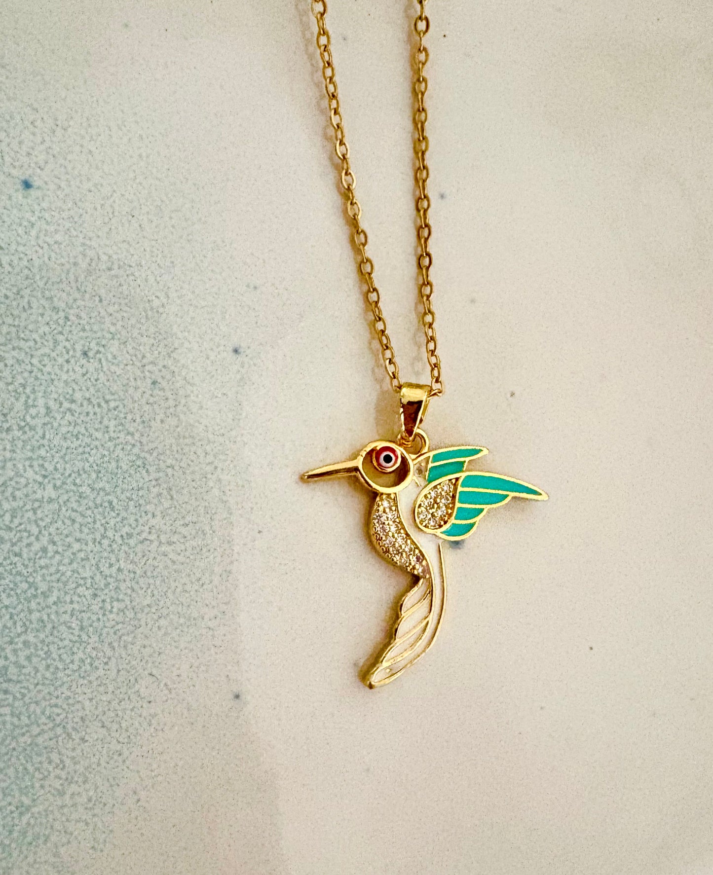 Gold and silver hummingbird necklaces displayed on mannequin