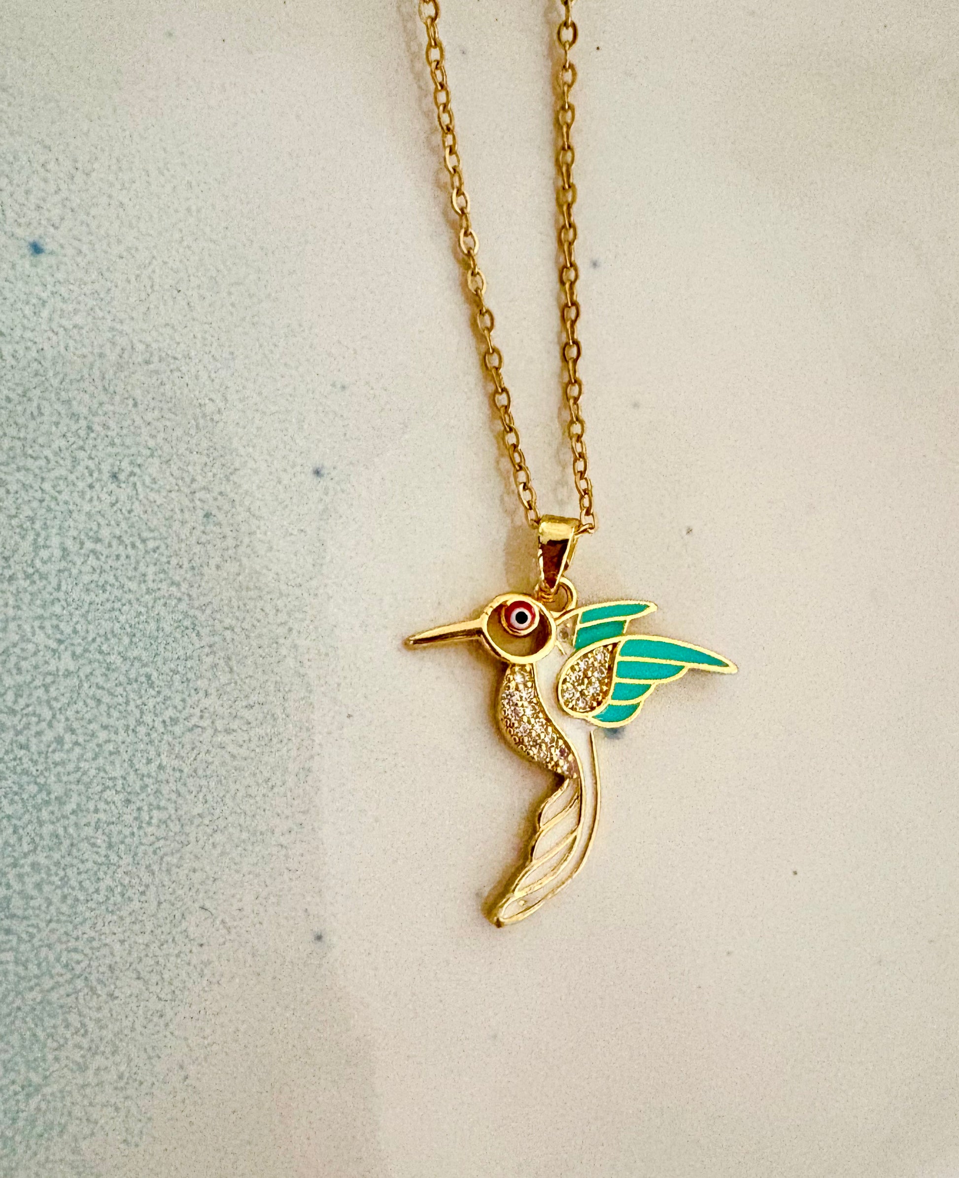 Gold and silver hummingbird necklaces displayed on mannequin