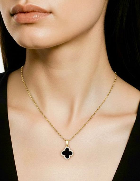 Gold necklace with a clover pendant worn by a person