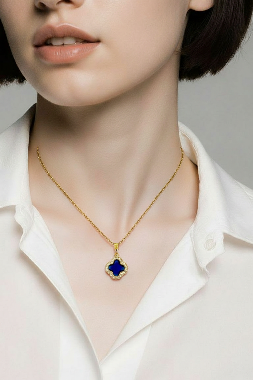 Gold necklace with a blue pendant worn by a person in a white shirt.
