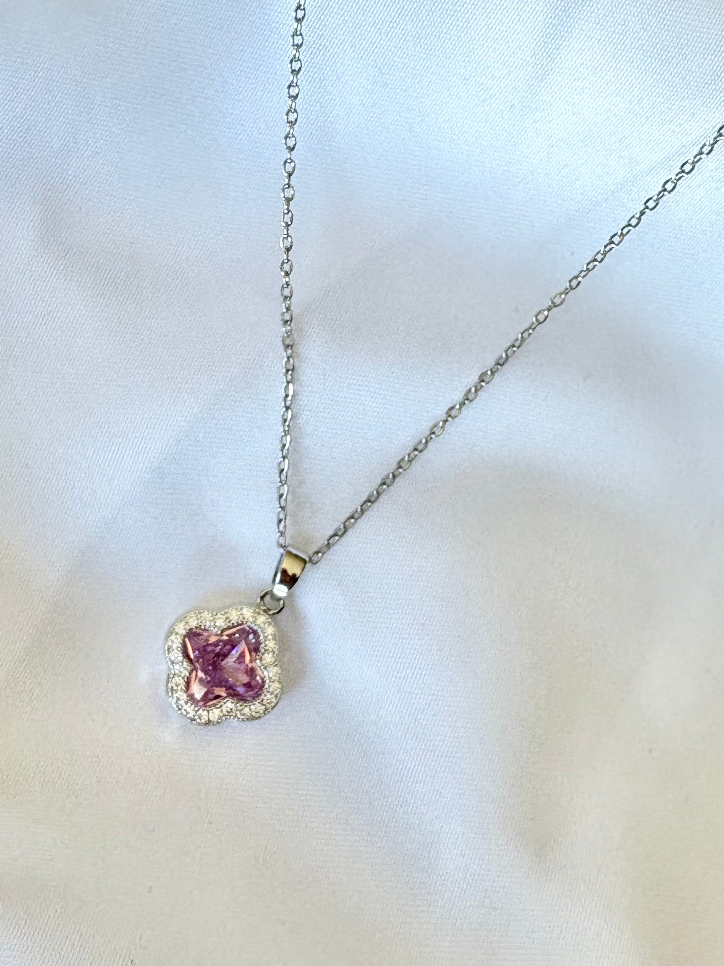 Close-up of pink clover charm necklace with zircon border on silver chain