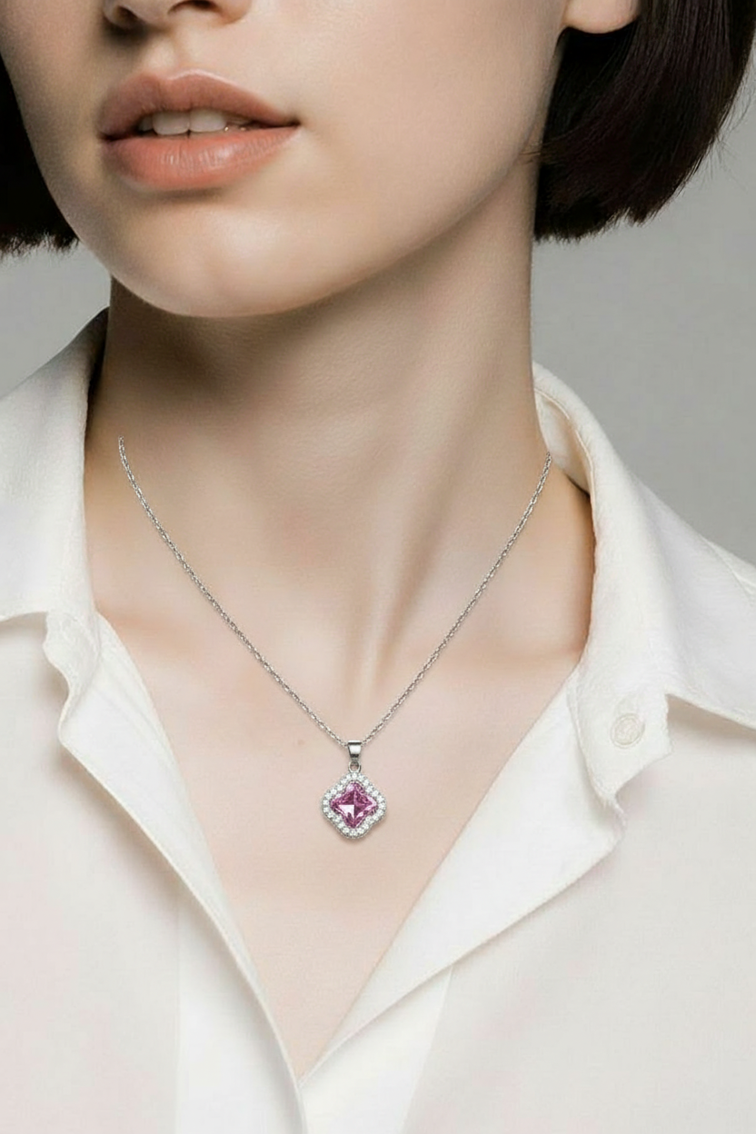 Necklace with a pink gemstone pendant worn by a person in a white shirt.