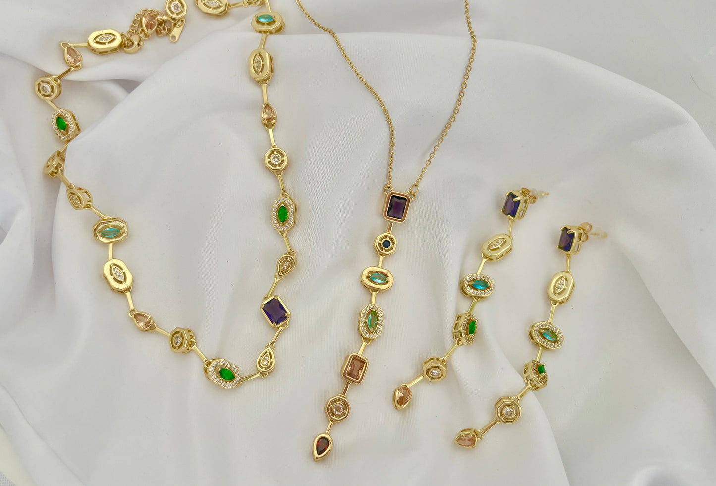 Gold jewelry set with gemstones on a white fabric background