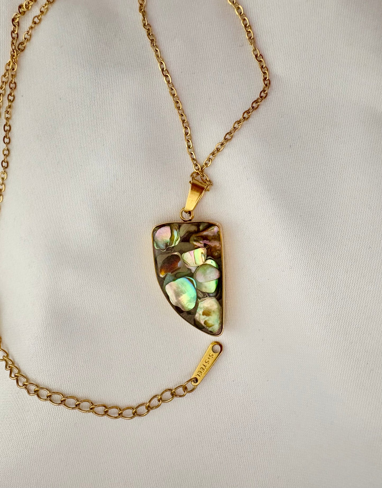 Gold necklace with a multicolored stone pendant on a white background