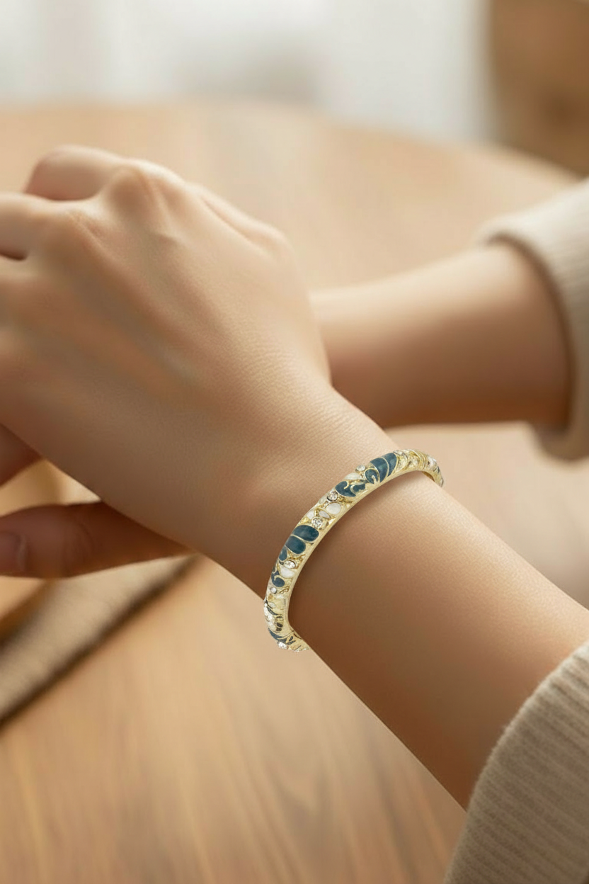Close-up of a hand wearing a gold bracelet with gemstones on a blurred background