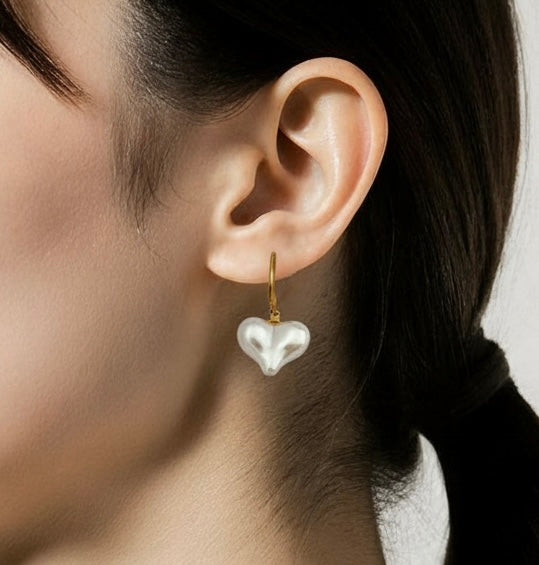 Gold lever-back earrings with baroque-style pearl heart charm. 