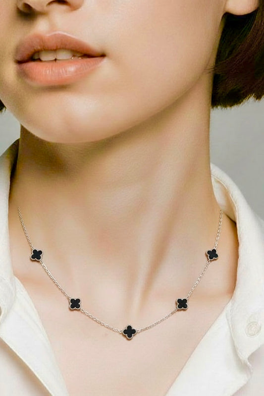 Necklace with black clover pendants worn by a person