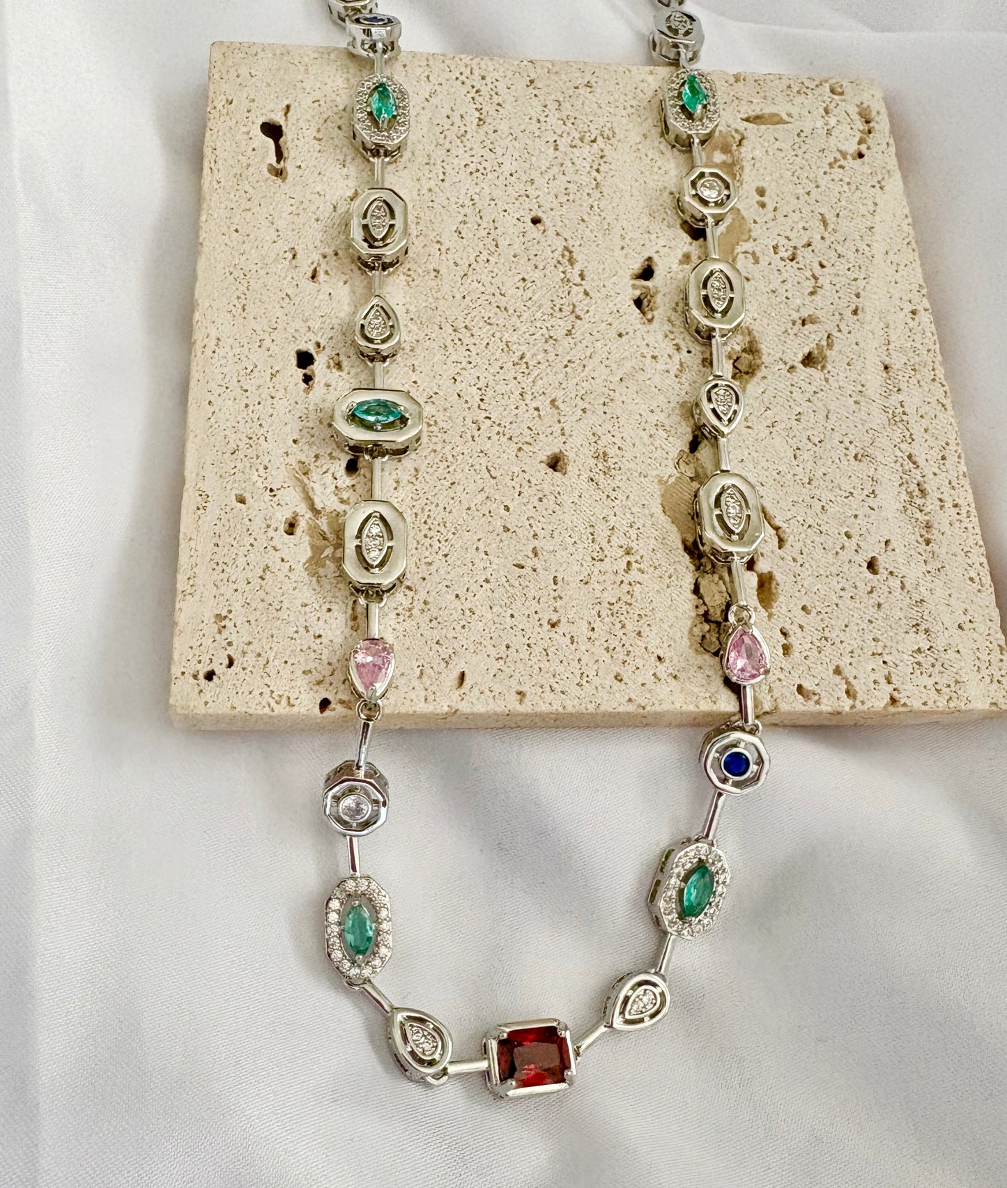 Necklace with gemstones on a textured beige surface