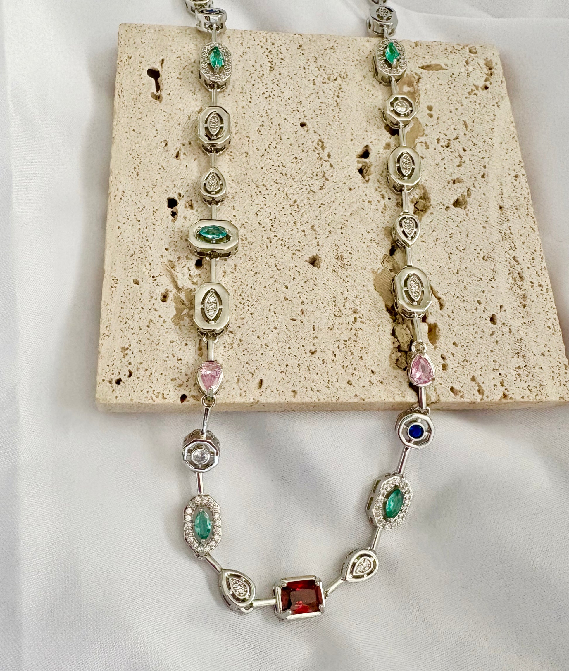 Necklace with gemstones on a textured beige surface