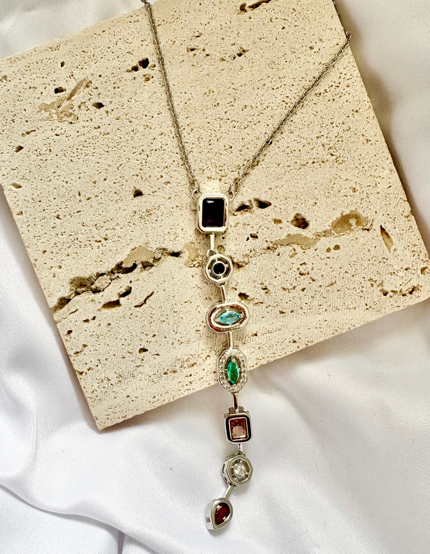 Necklace with gemstones on a textured beige surface