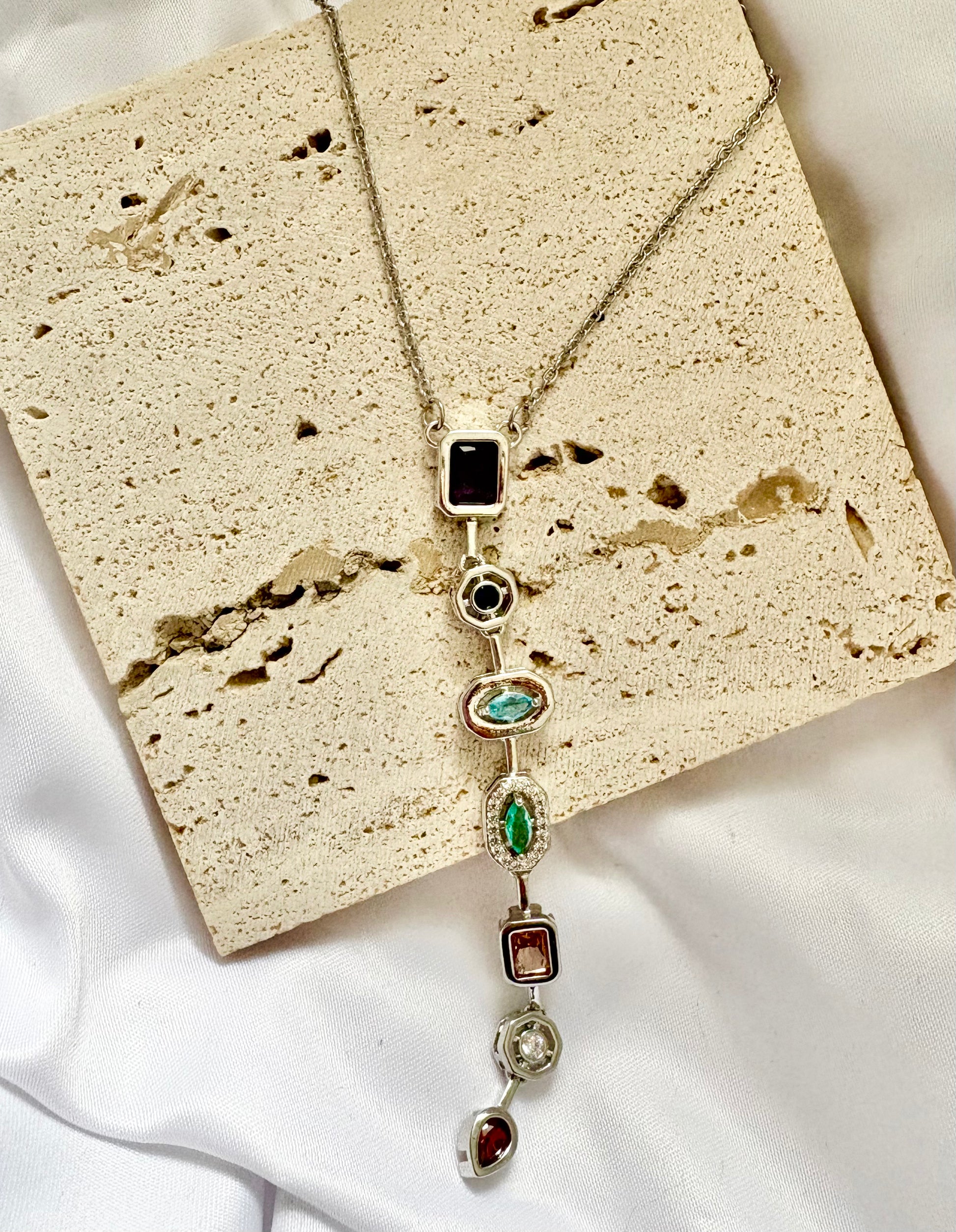 Necklace with gemstones on a textured beige surface