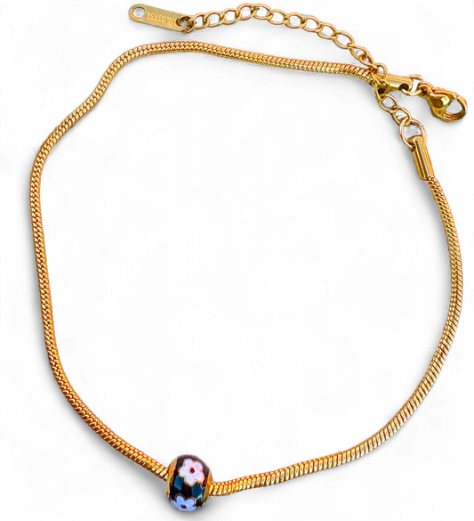 Gold bracelet with a blue bead on a white background